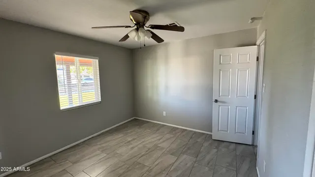 a view of empty room with wooden floor and fan