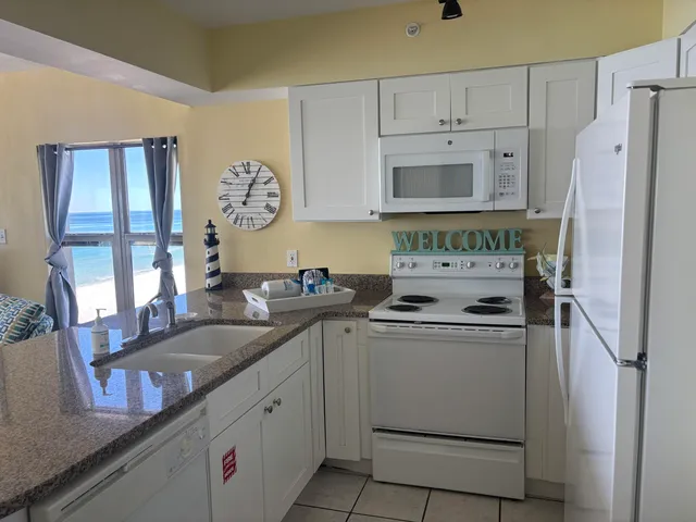 a kitchen with granite countertop a sink stove and refrigerator