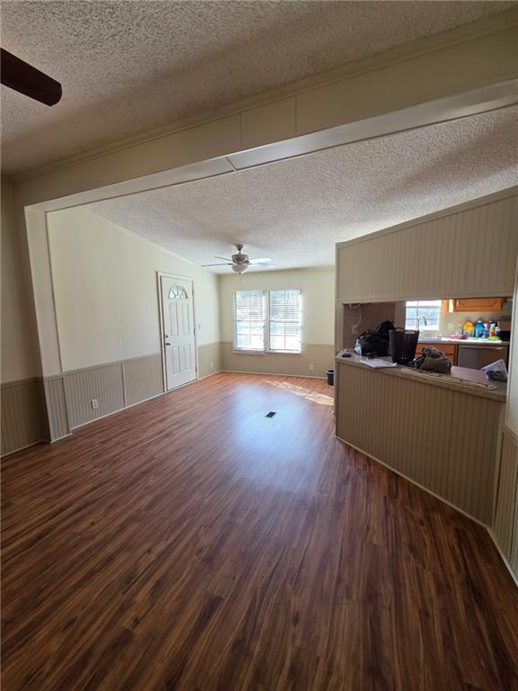 129 Bishop Road Smiths Station, AL 36877 - Photo 9 of 24 Living room featuring a ceiling fan, a textured ceiling, dark wood-type flooring, a wainscoted wall, and healthy amount of natural light