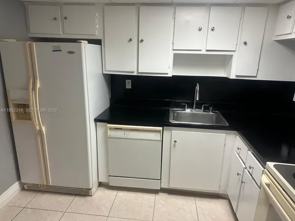 a kitchen with granite countertop white cabinets and refrigerator