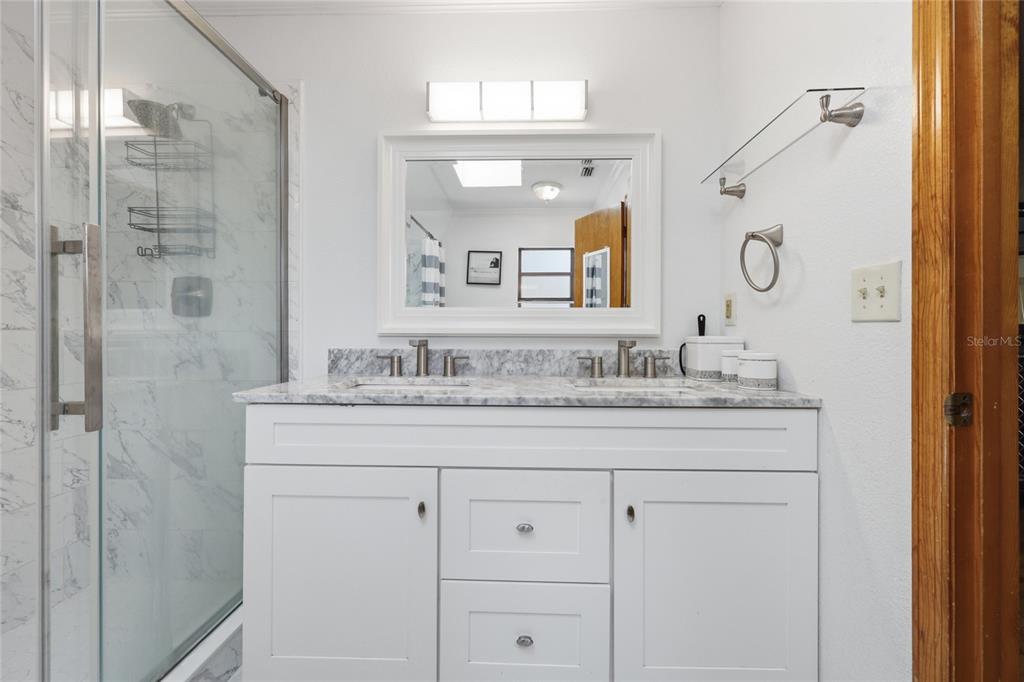 16104 Southwest 48th Circle Ocala, FL 34473 - Photo 15 of 34 a bathroom with a granite countertop sink a mirror and a shower
