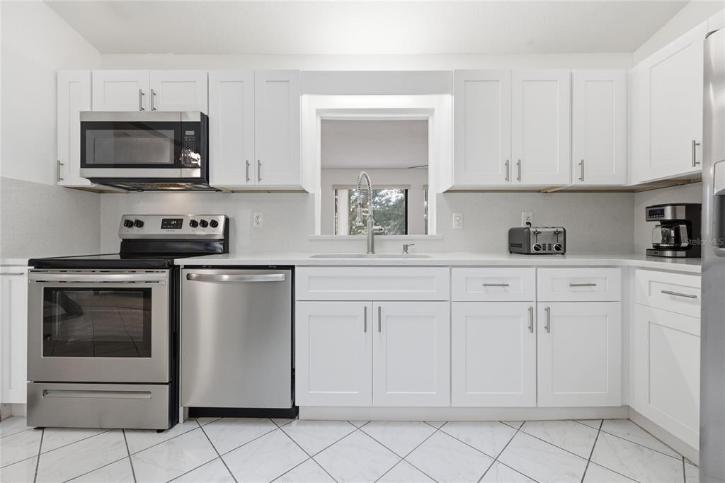 16104 Southwest 48th Circle Ocala, FL 34473 - Photo 7 of 34 a kitchen with white cabinets stainless steel appliances and sink