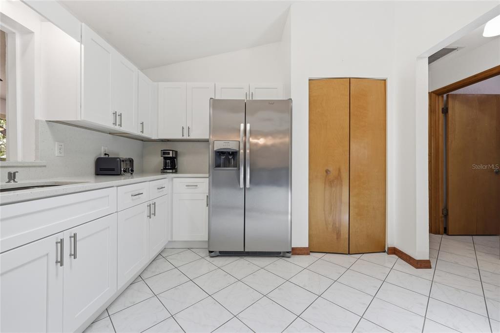 16104 Southwest 48th Circle Ocala, FL 34473 - Photo 8 of 34 a kitchen with white cabinets and refrigerator