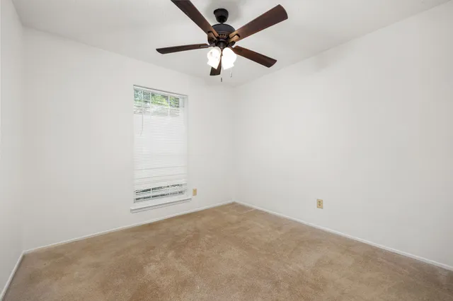 an empty room with a ceiling fan and carpet