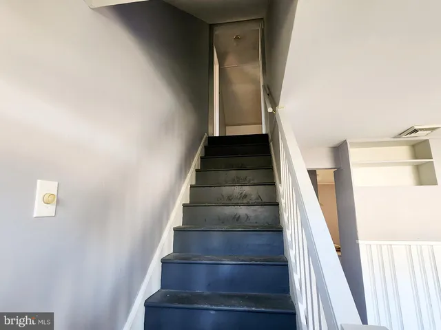 a view of staircase with wooden floor and white walls