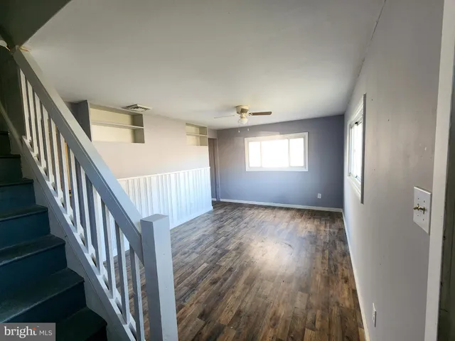 a view of an empty room with wooden floor and windows
