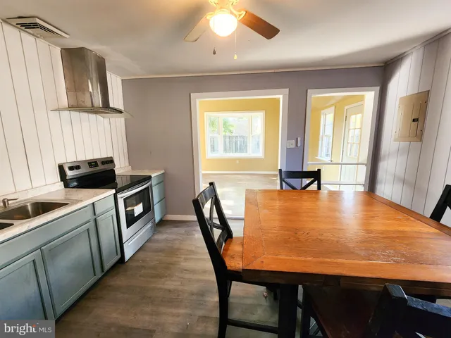 a kitchen with stainless steel appliances granite countertop a stove top oven a sink a dining table and chairs