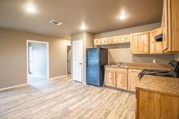a kitchen with granite countertop a refrigerator and a stove top oven