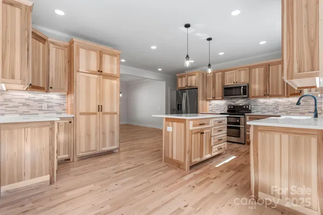 a kitchen with stainless steel appliances granite countertop a refrigerator a stove a sink and white cabinets with wooden floor