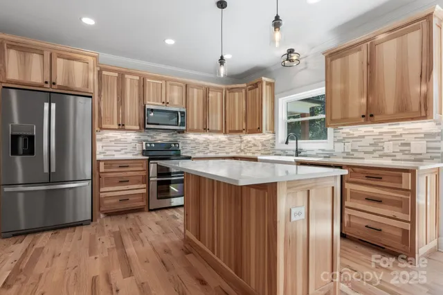 a kitchen with kitchen island granite countertop a stove top oven a refrigerator cabinets and wooden floor