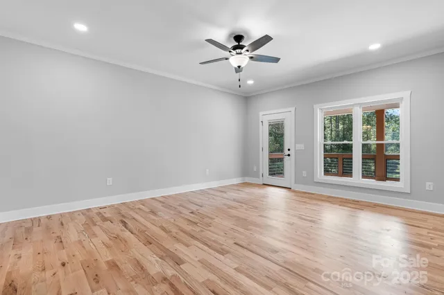 a view of empty room with wooden floor and ceiling fan