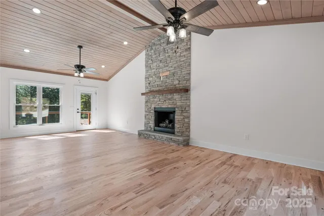 an empty room with windows chandelier fan and fireplace