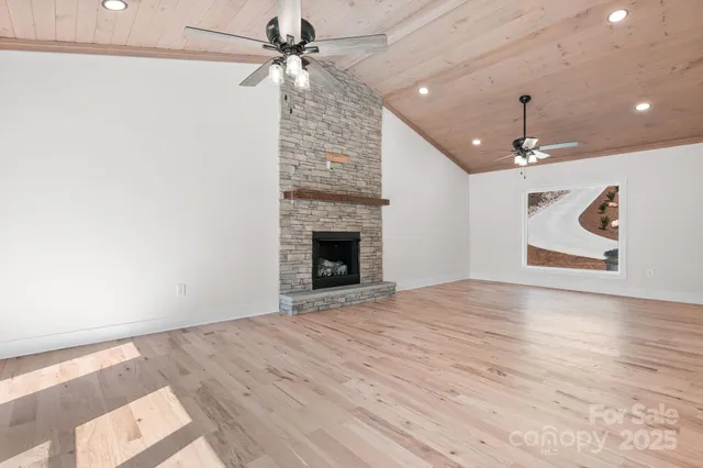 an empty room with chandelier fan and wooden floor