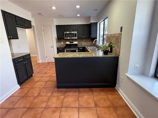 a kitchen with stainless steel appliances a refrigerator a stove a microwave and a sink