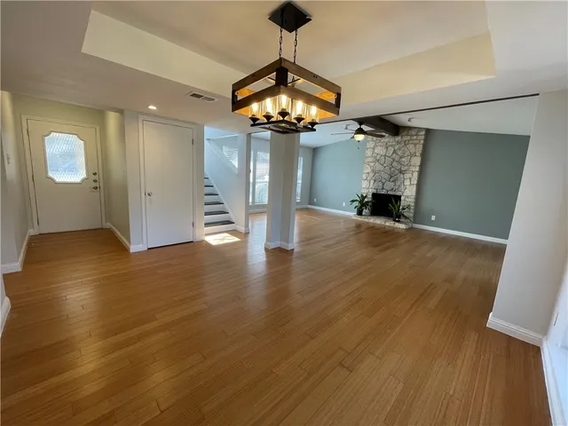 a view of an empty room with a fireplace and wooden floor