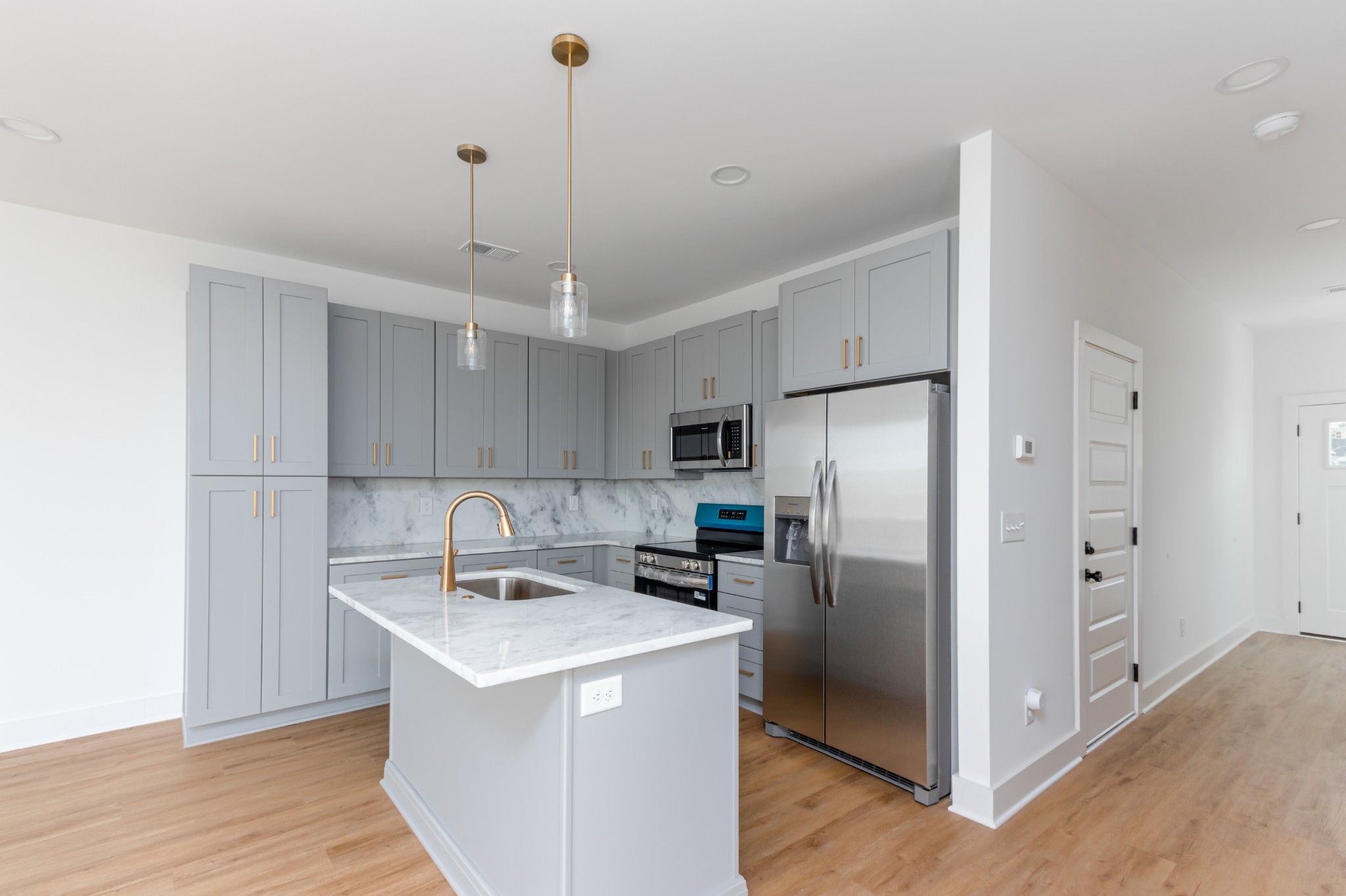 a kitchen with stainless steel appliances granite countertop a refrigerator a sink a stove and a refrigerator