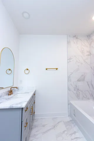 a bathroom with a granite countertop sink a mirror and a bathtub