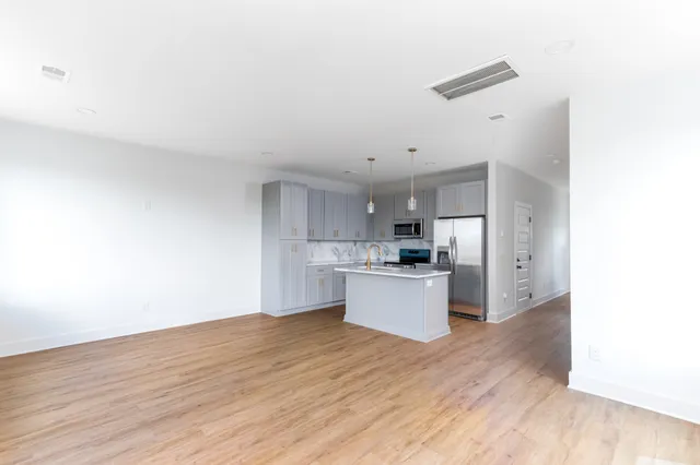 a view of kitchen and empty room with wooden floor