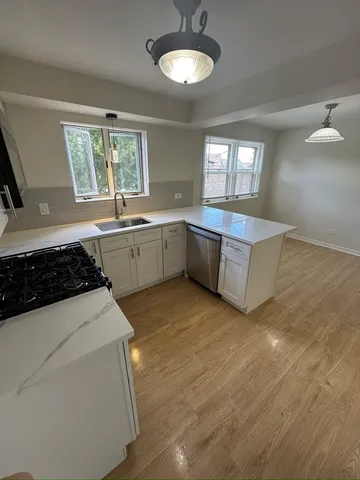 a kitchen with a sink a stove a window and cabinets