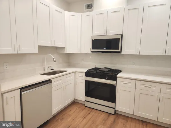 a kitchen with stainless steel appliances granite countertop white cabinets a sink and dishwasher