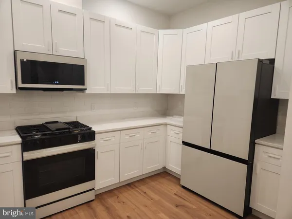 a kitchen with stainless steel appliances white cabinets and a stove a refrigerator with wooden floors