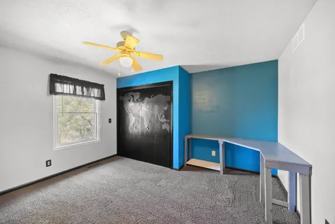 a view of an empty room with window and chandelier fan