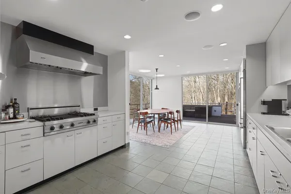 a large white kitchen with a stove a sink a dining table and chairs