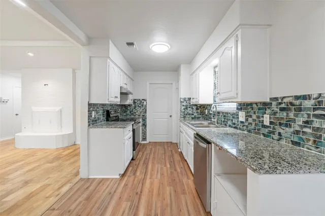 a kitchen with granite countertop a sink a counter top space stainless steel appliances and cabinets