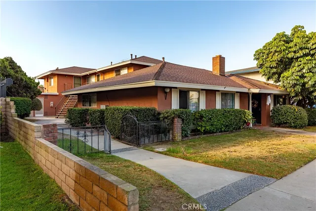 a view of a house with a small yard and a large tree