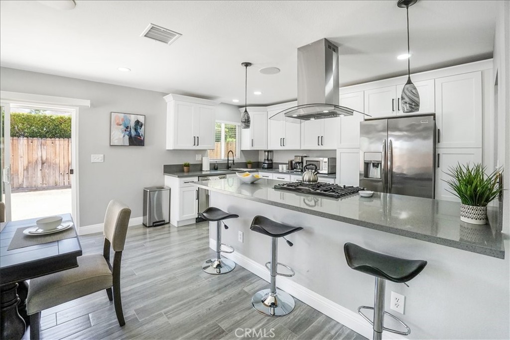 39120 Paradise Way Cathedral City, CA 92234 - Photo 9 of 41 a kitchen with stainless steel appliances a dining table chairs stove and white cabinets