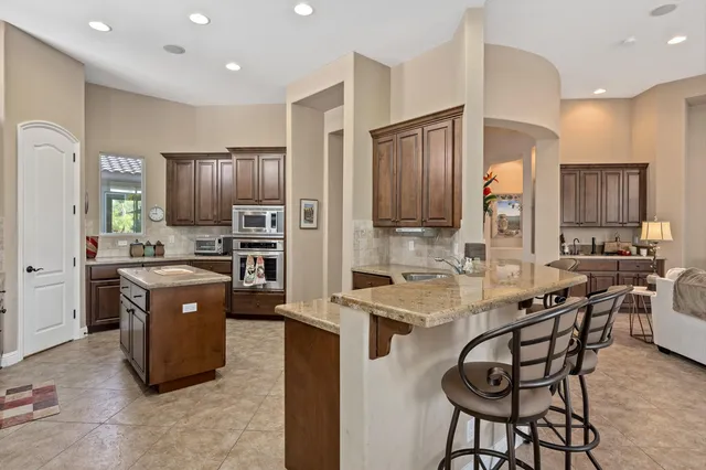 a kitchen with stainless steel appliances a sink a stove a refrigerator cabinets and a dining table