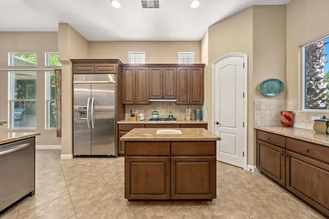 a kitchen with stainless steel appliances granite countertop a refrigerator a sink and a stove