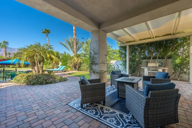 a view of a patio with couches chairs potted plants and floor to ceiling window yard
