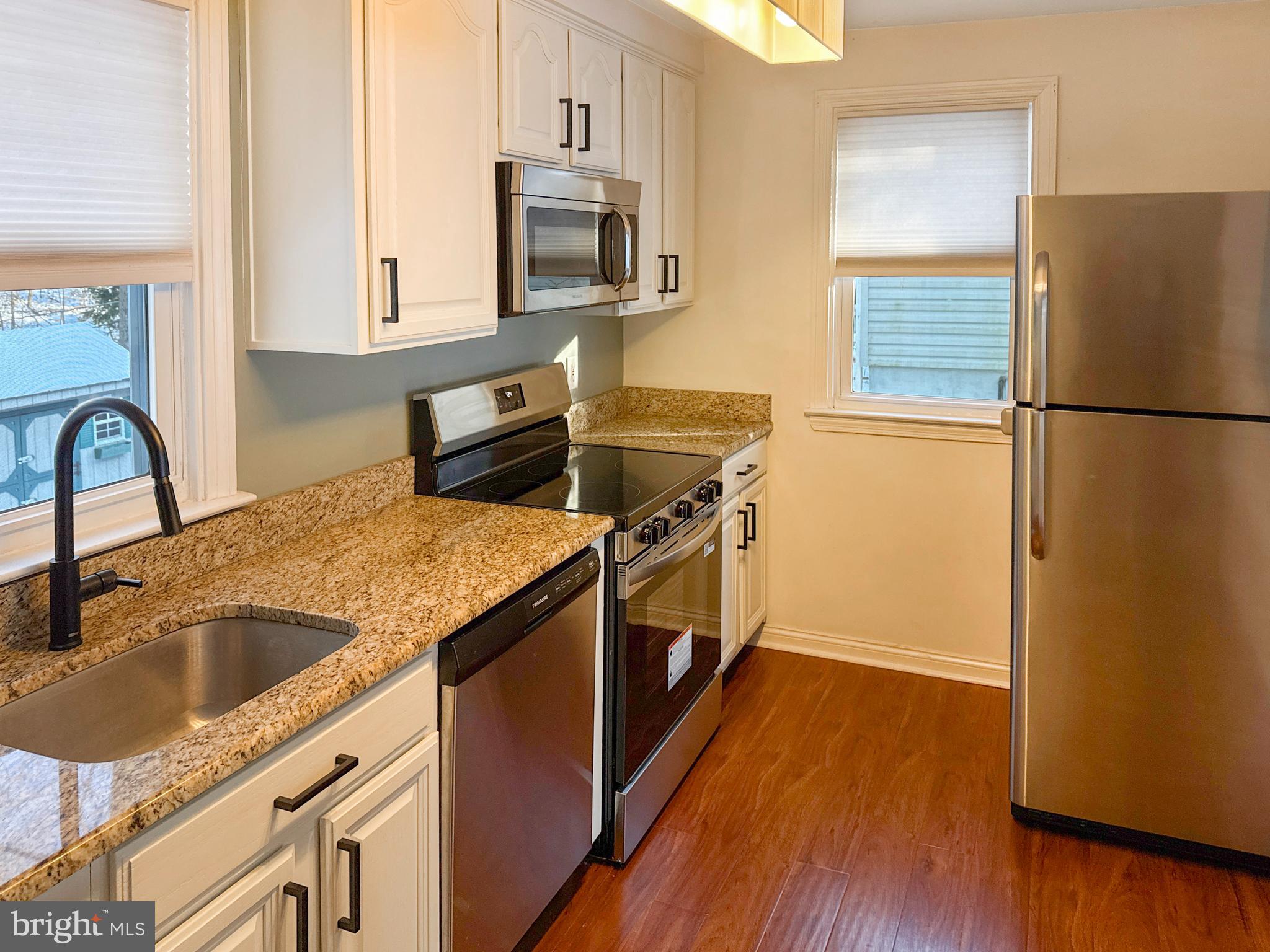 133 North Line Road Newtown Square, PA 19073 - Photo 6 of 23 a kitchen with stainless steel appliances granite countertop a refrigerator a sink a stove a microwave and wooden floor