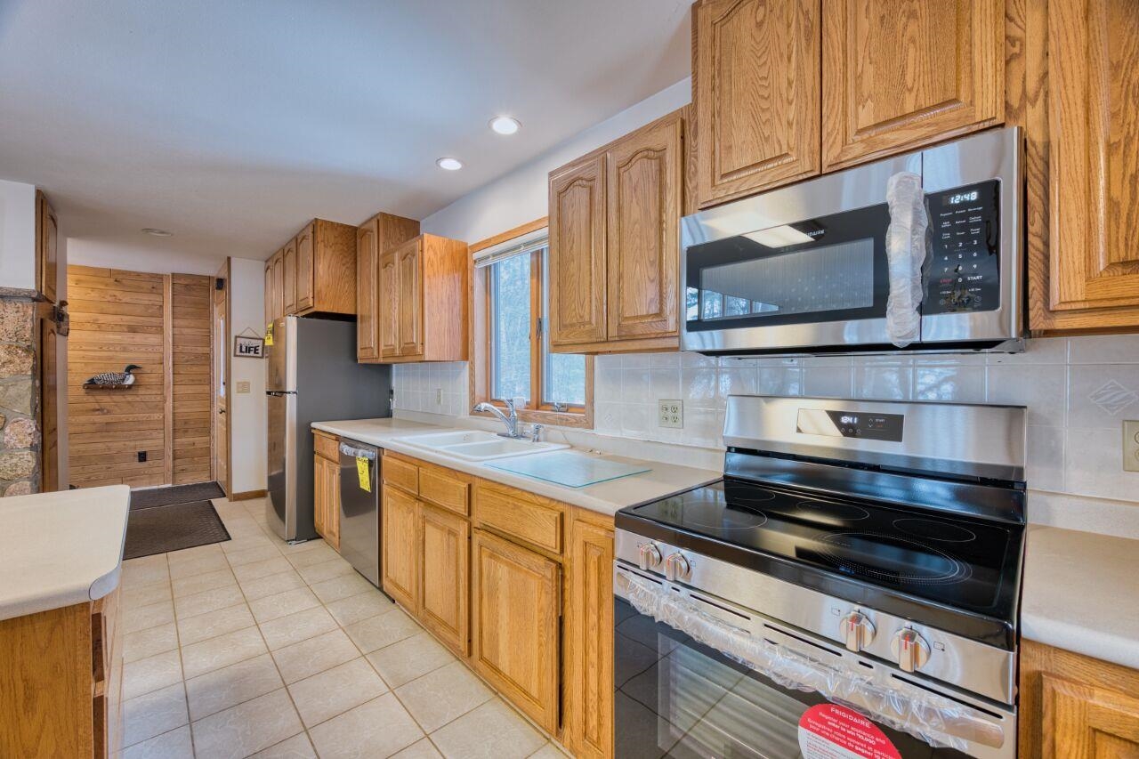 6312 Juniper Lane Gilbert, MN 55741 - Photo 13 of 50 Kitchen with a sink, backsplash, light countertops, and appliances with stainless steel finishes