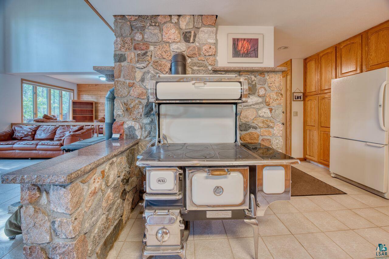 6312 Juniper Lane Gilbert, MN 55741 - Photo 14 of 50 Kitchen with light tile patterned floors, a kitchen bar, kitchen peninsula, and white fridge