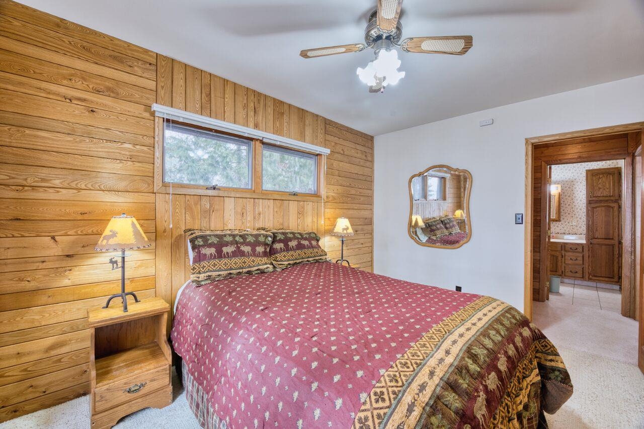 6312 Juniper Lane Gilbert, MN 55741 - Photo 15 of 50 Carpeted bedroom featuring wooden walls, ensuite bathroom, and ceiling fan