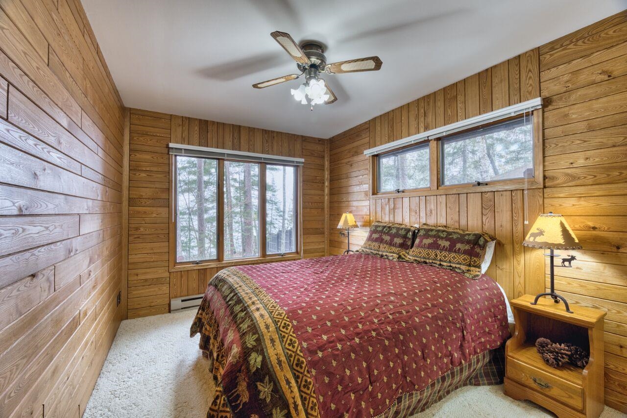 6312 Juniper Lane Gilbert, MN 55741 - Photo 16 of 50 Carpeted bedroom featuring wood walls, a baseboard heating unit, and a ceiling fan