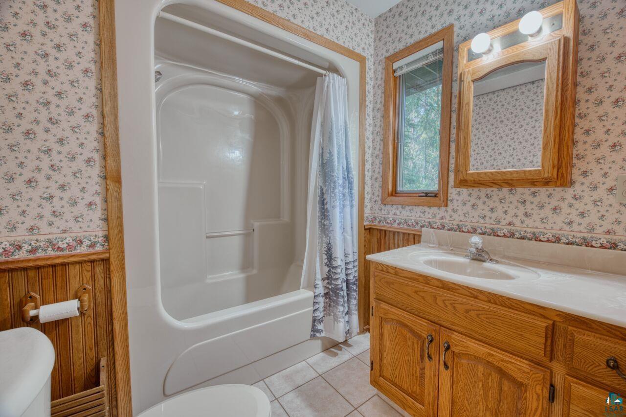 6312 Juniper Lane Gilbert, MN 55741 - Photo 17 of 50 Full bathroom featuring shower / bath combo, tile patterned flooring, toilet, and vanity