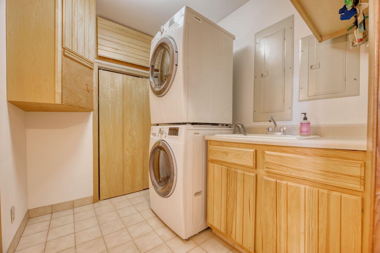 6312 Juniper Lane Gilbert, MN 55741 - Photo 23 of 50 Washroom with stacked washer and clothes dryer, cabinets, light tile patterned floors, sink, and electric panel