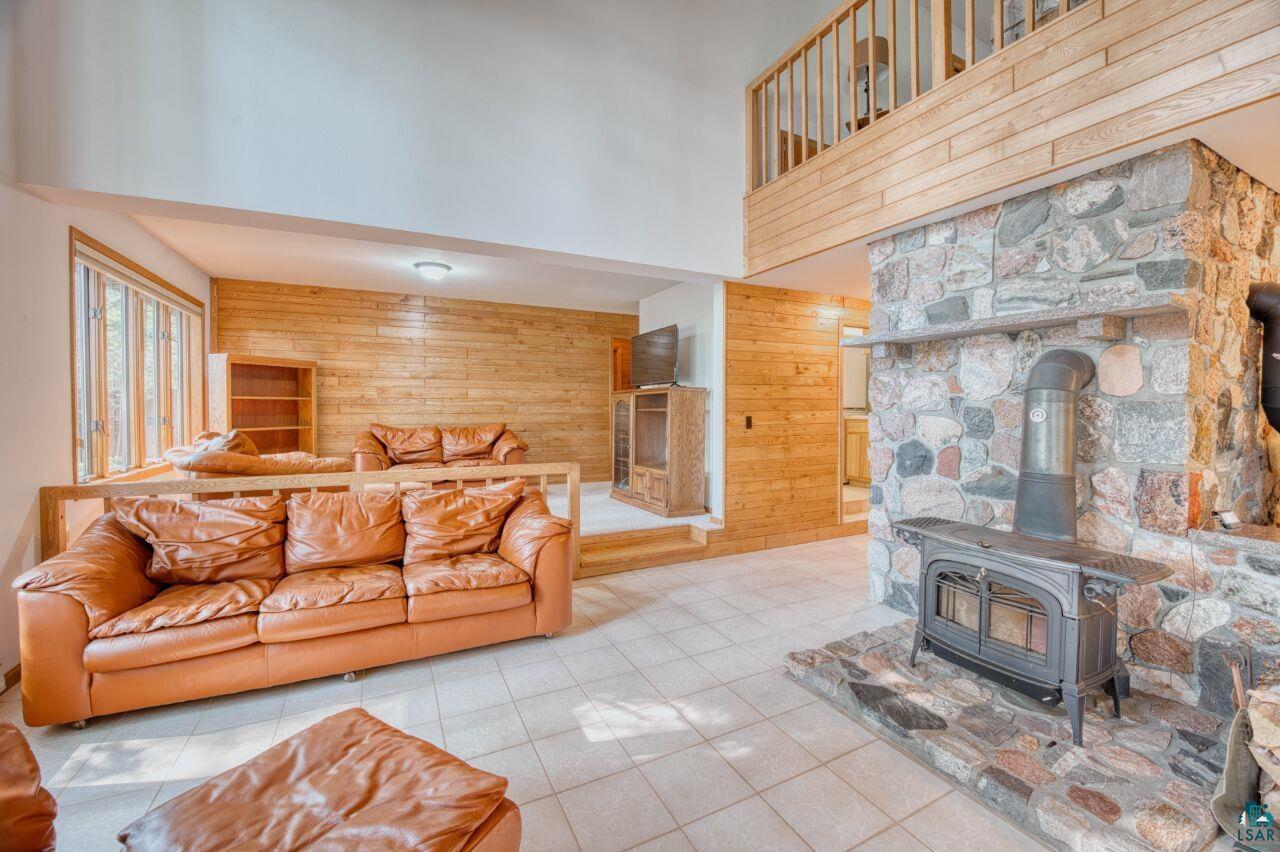 6312 Juniper Lane Gilbert, MN 55741 - Photo 3 of 50 Tiled living room featuring a wood stove, wood walls, and a towering ceiling