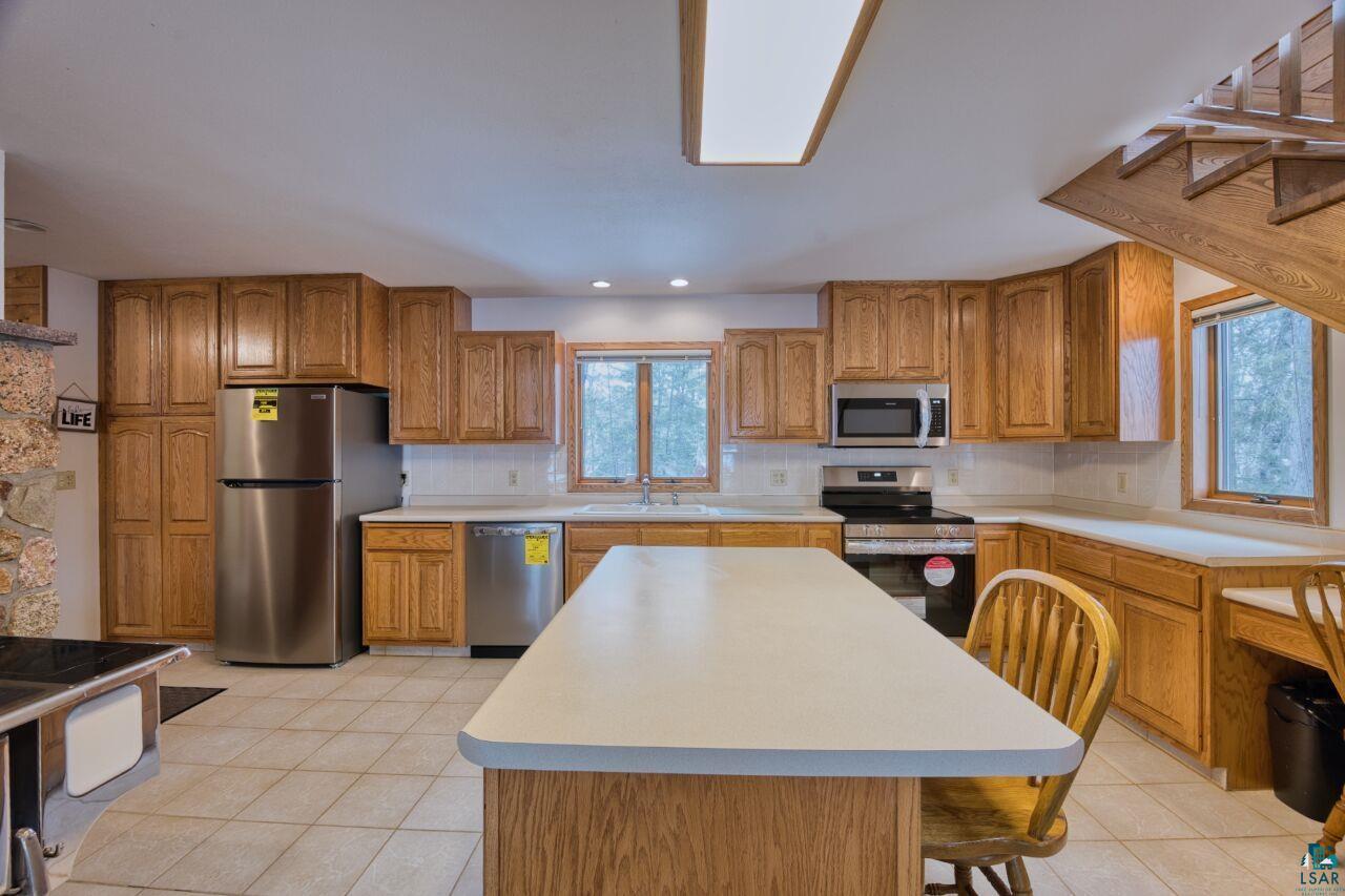 6312 Juniper Lane Gilbert, MN 55741 - Photo 9 of 50 Kitchen featuring brown cabinetry, light countertops, backsplash, and appliances with stainless steel finishes
