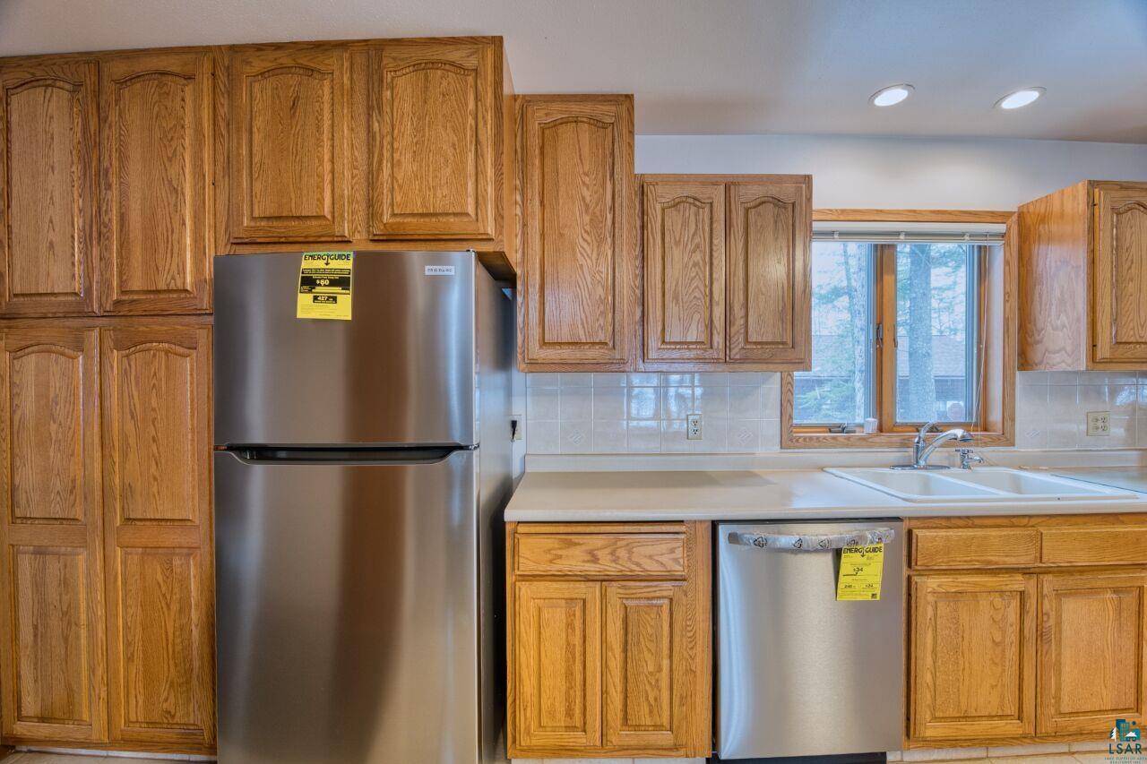 6312 Juniper Lane Gilbert, MN 55741 - Photo 10 of 50 Kitchen featuring stainless steel appliances, brown cabinetry, a sink, and decorative backsplash