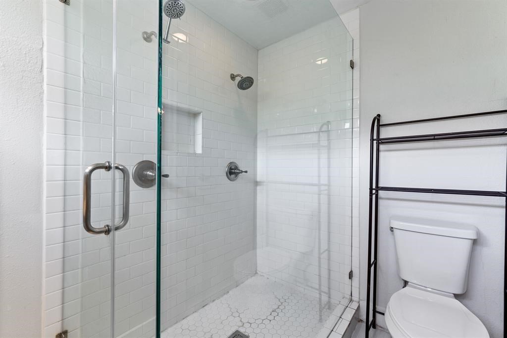 1305 Idylwild Street Houston, TX 77009 - Photo 28 of 31 This bathroom features a modern walk-in shower with glass doors and white subway tile. There's a built-in shower niche for storage. Adjacent is a toilet, providing a clean and functional space.