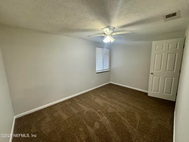 an empty room with windows and fan