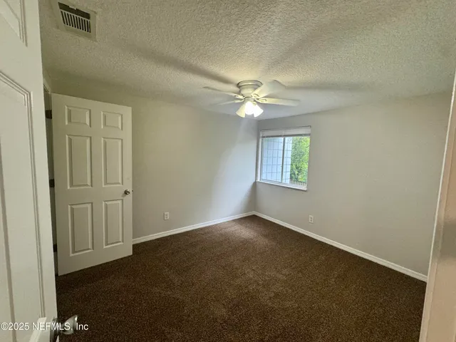 an empty room with windows and fan