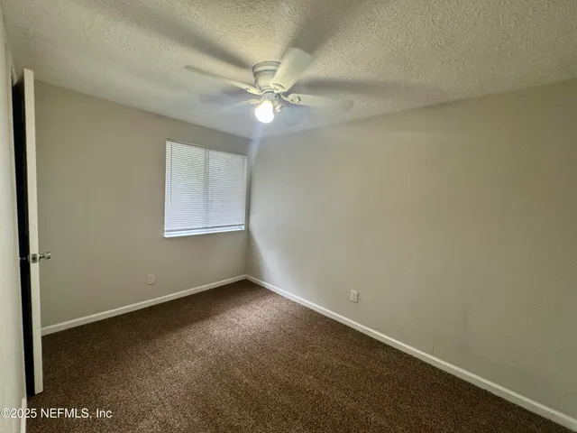 an empty room with a fan & a window