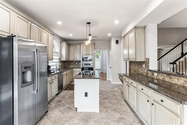 a kitchen with stainless steel appliances granite countertop a refrigerator and a stove top oven