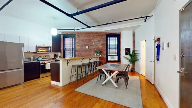 a dining room with wooden floor and stainless steel appliances