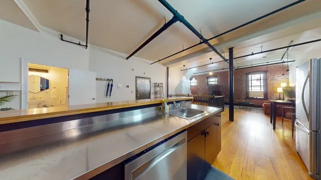 a hallway with a large counter space wooden floor and a view of living room